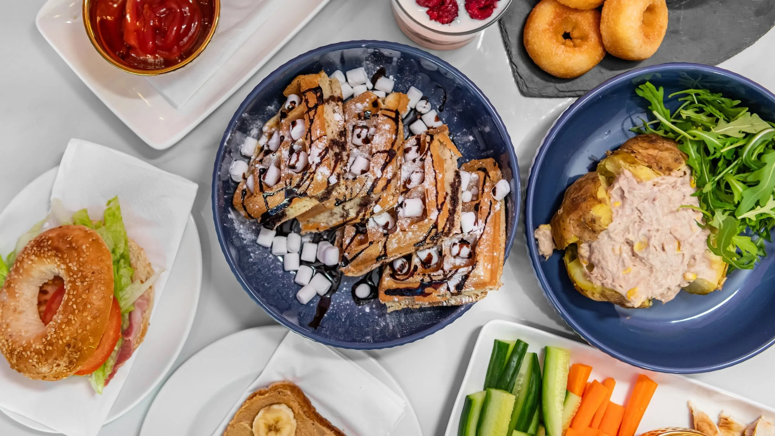 Waffles with marshmallows, a bagel, a jacket potato and doughnuts