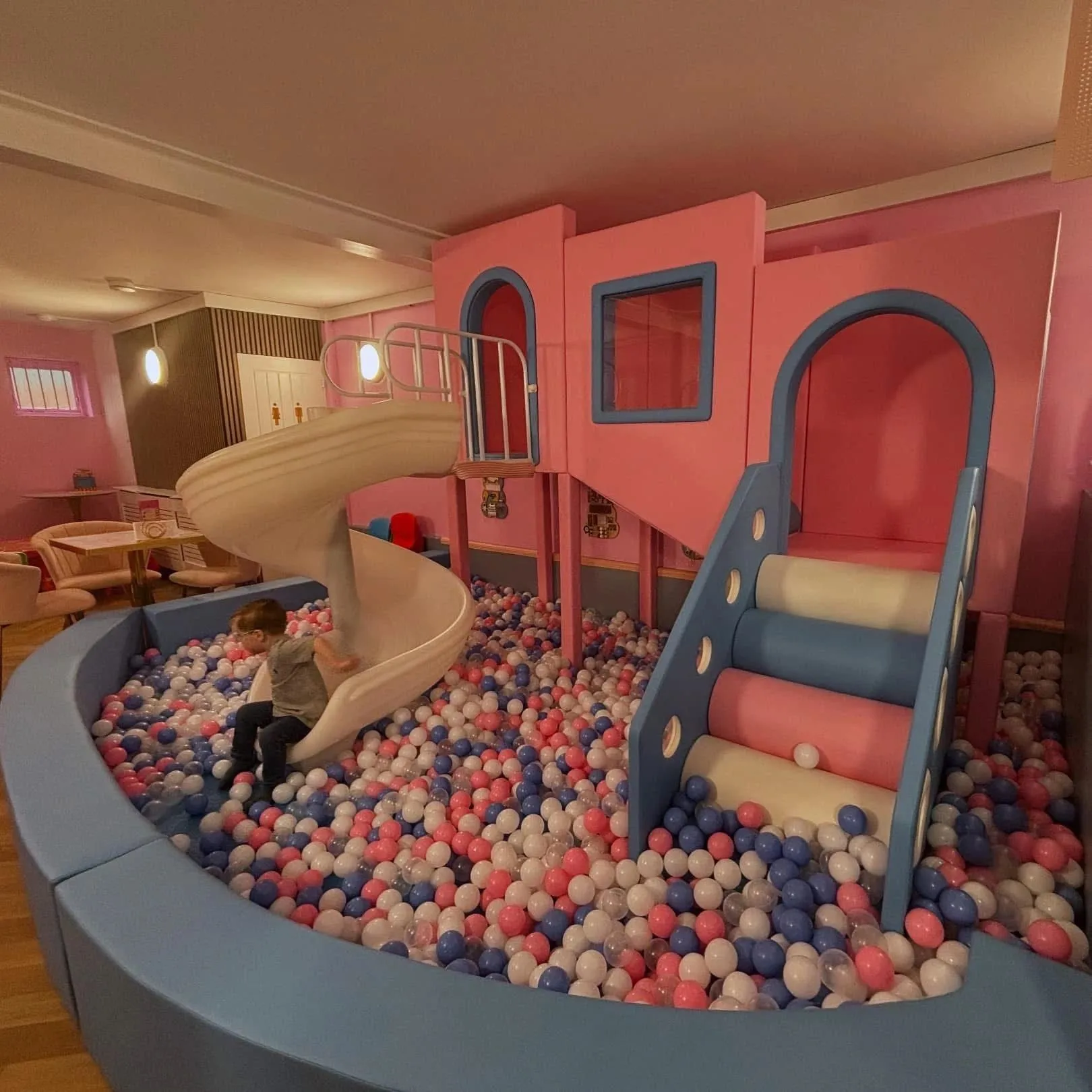 The pink play frame at Peekaboo & Brew, with its spiral slide, arched windows and ball pit